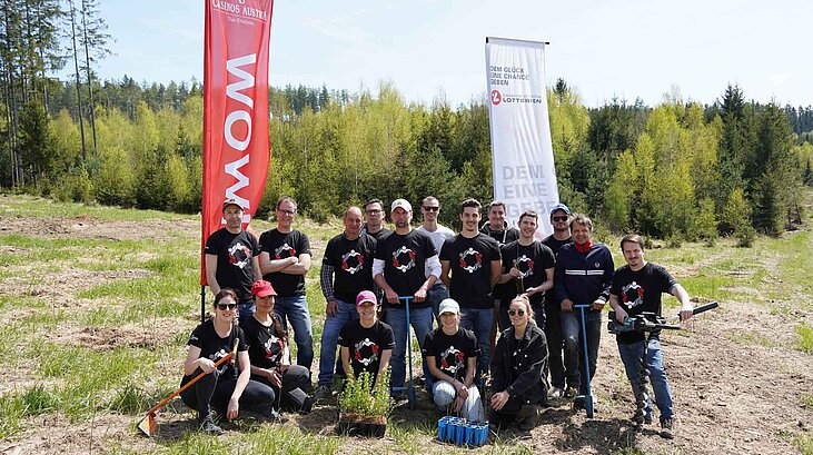 Gruppe von 17 Personen im Wald4Leben vor zwei Fahnen von Casinos Austria und den Österreichischen Lotterien .